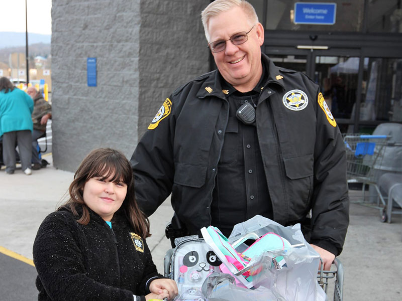 Child and cop with shopping cart full of toys