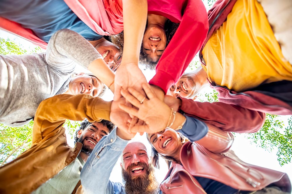 Diverse group of young people joining hands in middle